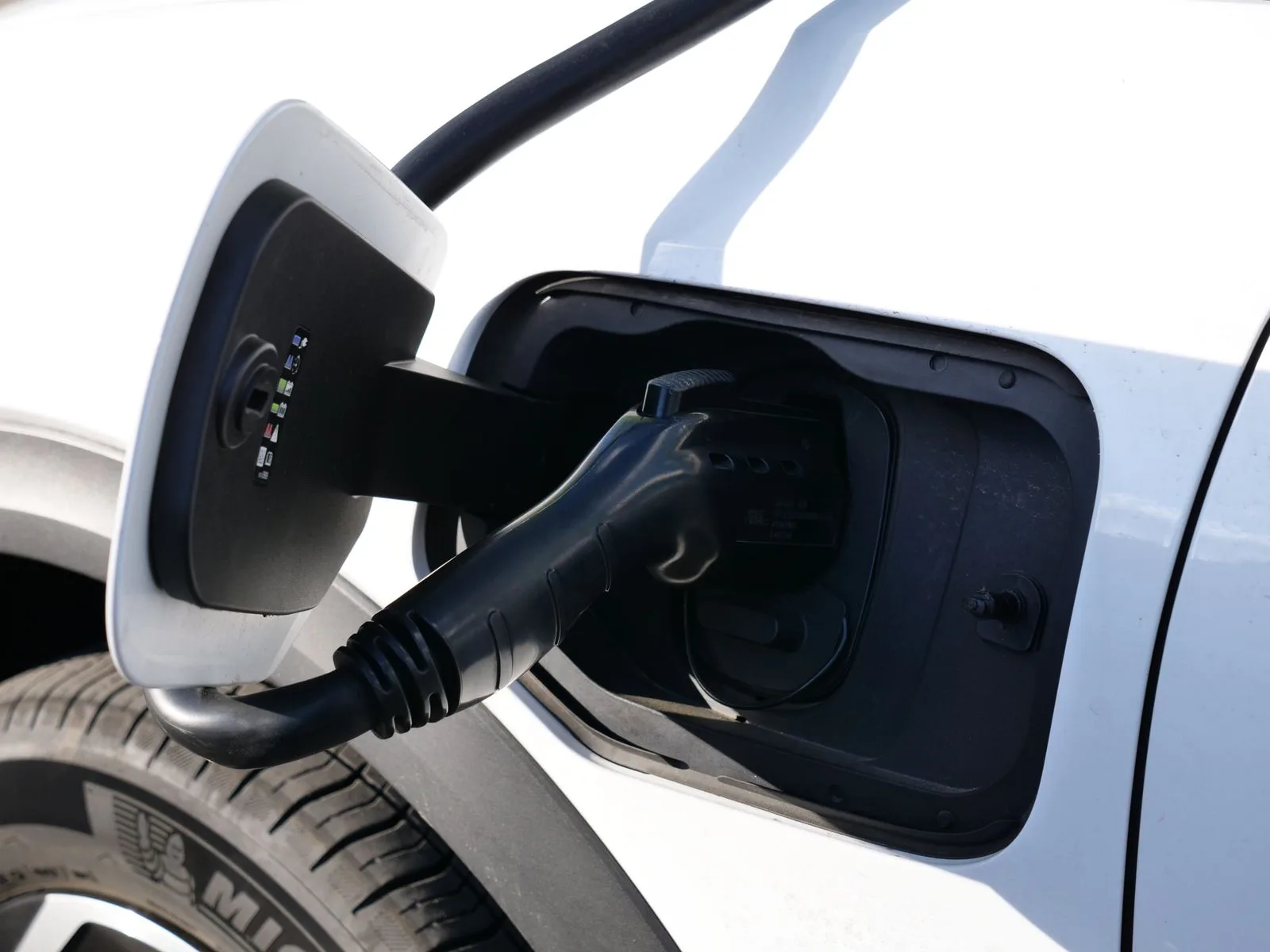 Close-up of an EV charging connector plugged into a vehicle's charge port