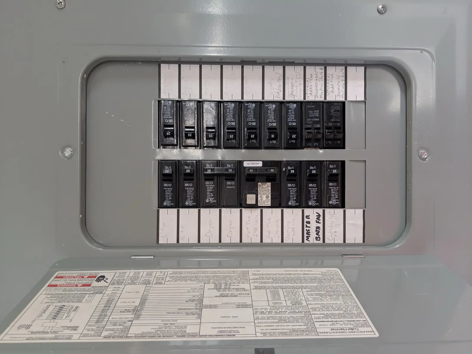 Open breaker panel with a hand-written circuit directory taped to the door