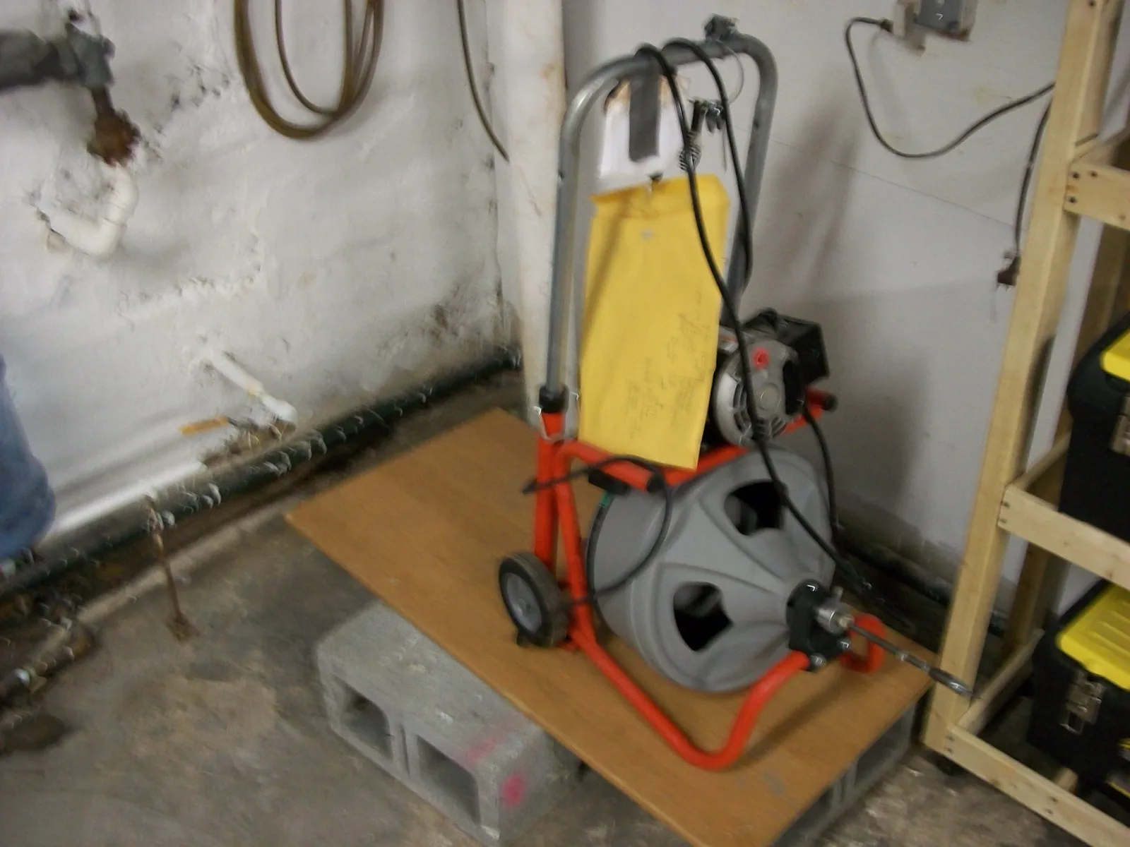 Cart-mounted drain cleaning machine staged in a basement