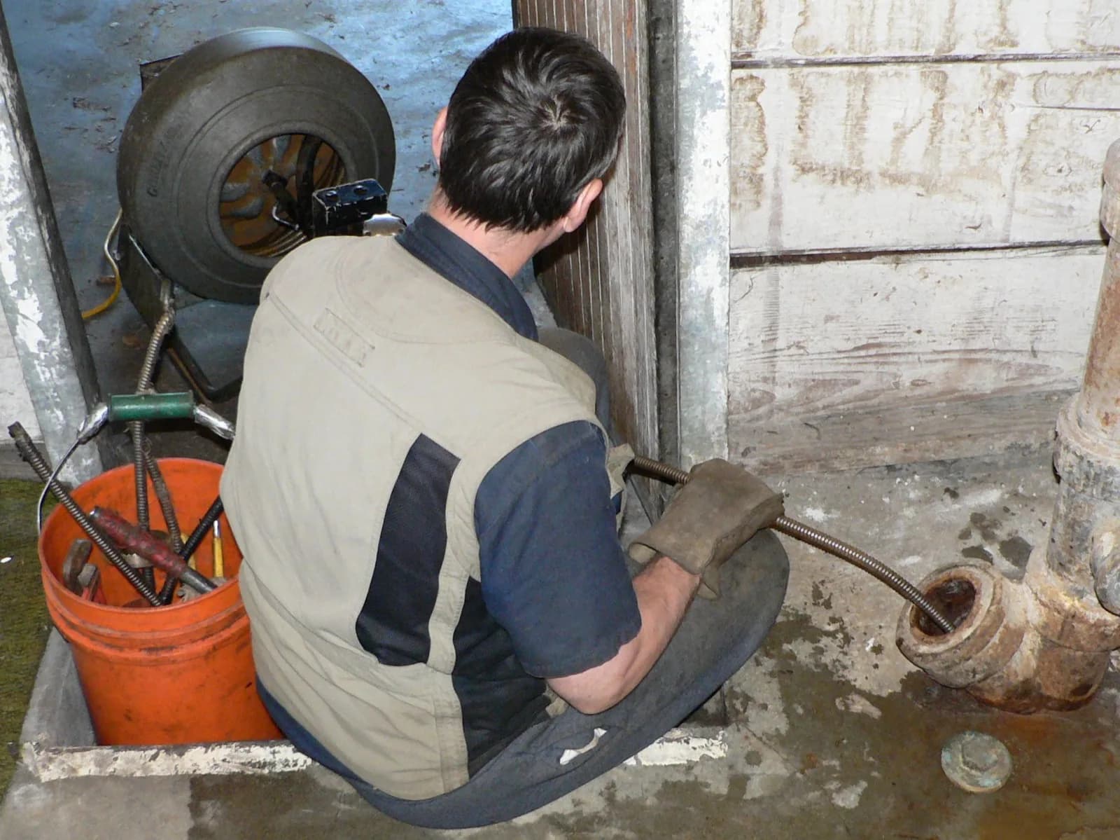Technician feeding a drain snake into a floor cleanout