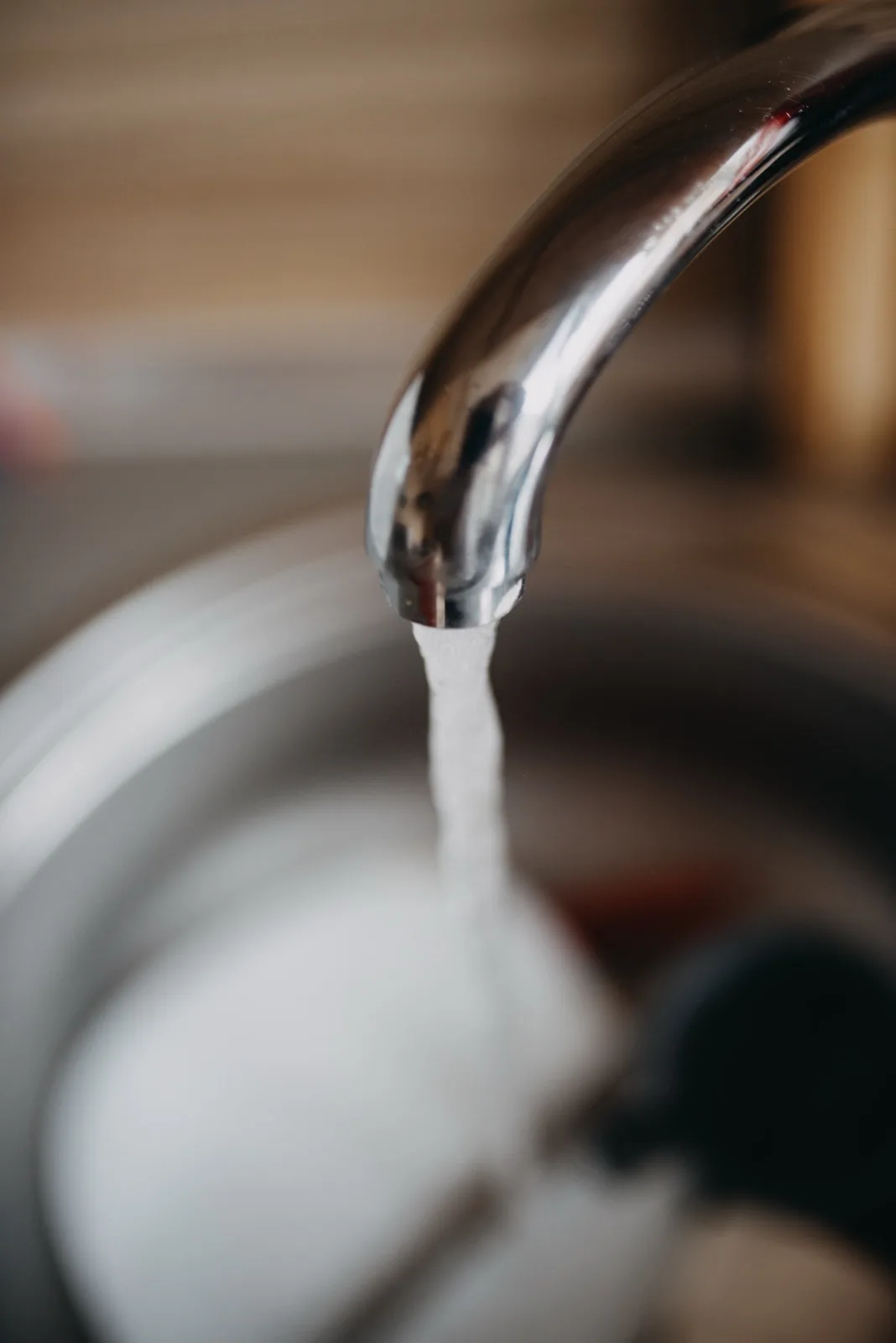 Water running from a kitchen faucet into a stainless sink