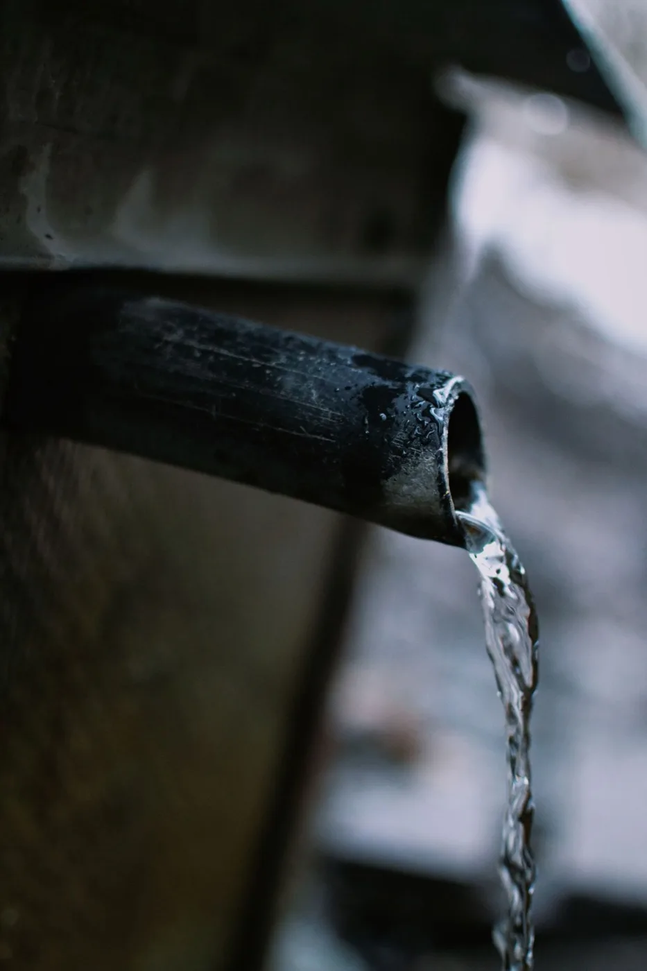 Water flowing steadily from an old exterior pipe fitting