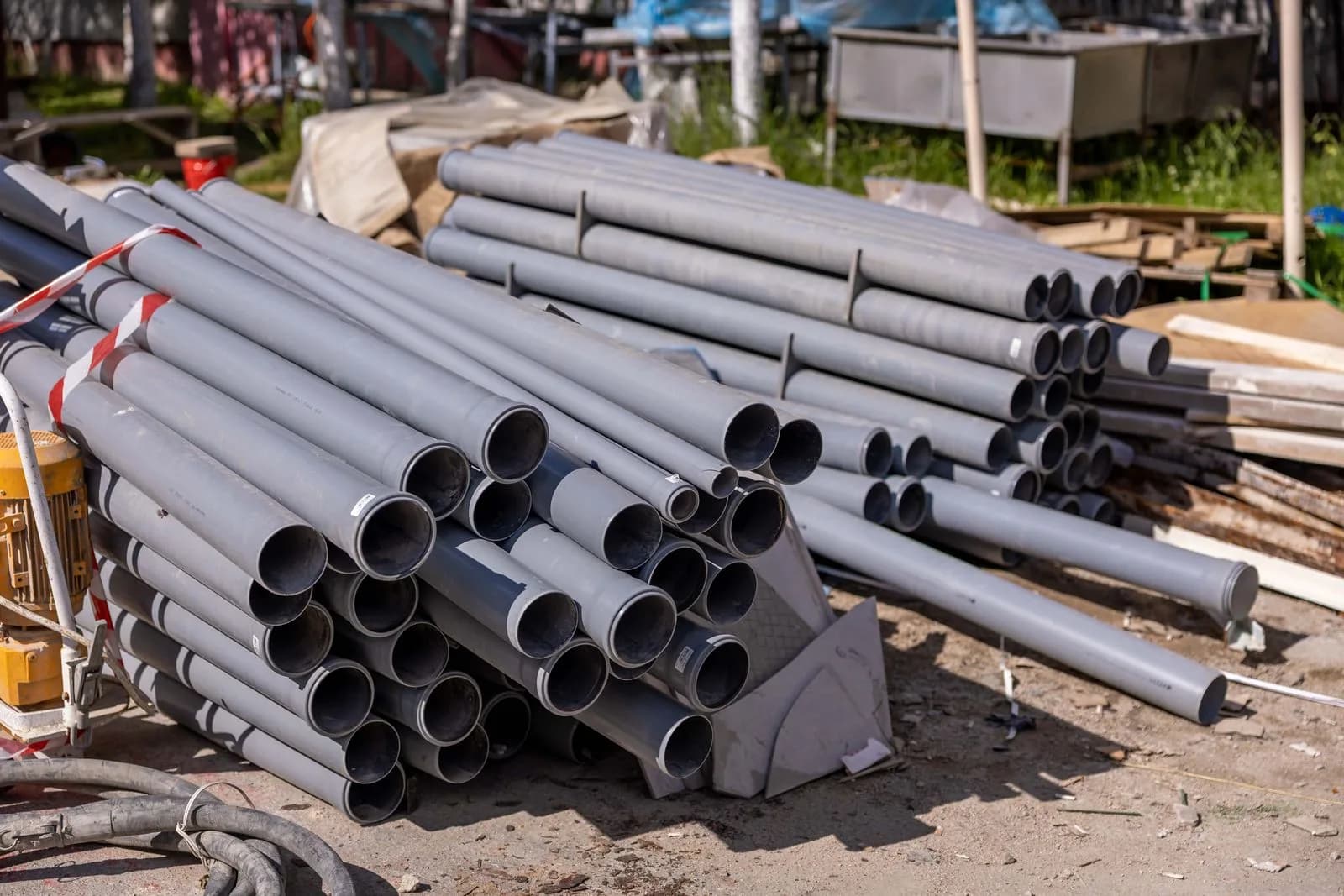 Stack of PVC sewer pipe sections staged at a job site